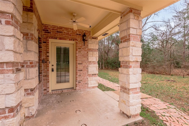 doorway to property featuring a patio area, ceiling fan, and brick siding