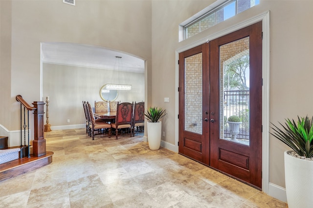 foyer entrance featuring crown molding, french doors, and a towering ceiling