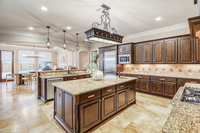 kitchen featuring pendant lighting, sink, a kitchen island with sink, built in appliances, and dark brown cabinets