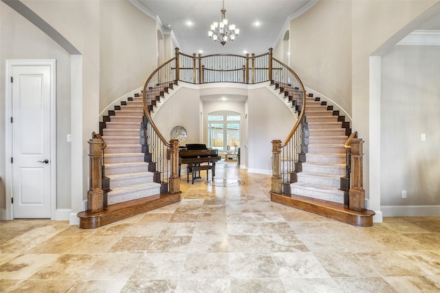 entryway featuring a towering ceiling, ornamental molding, and a chandelier