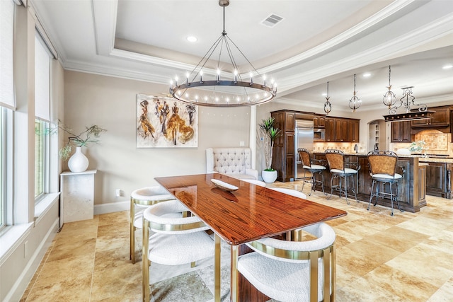 dining room with ornamental molding and a raised ceiling