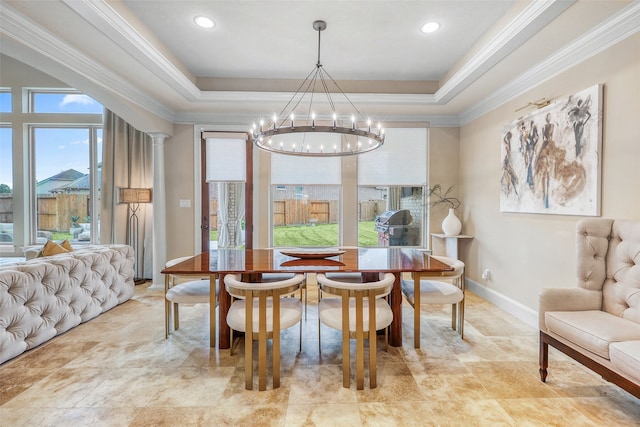 dining area featuring a notable chandelier, a tray ceiling, ornamental molding, and decorative columns