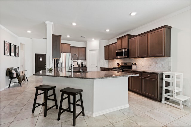 kitchen with crown molding, stainless steel appliances, sink, and dark stone counters