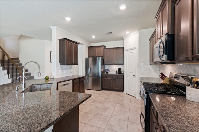 kitchen with dark brown cabinetry, appliances with stainless steel finishes, sink, and dark stone counters