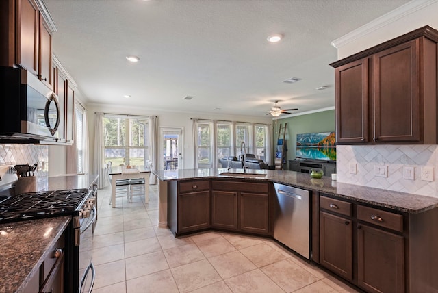 kitchen with crown molding, stainless steel appliances, sink, and dark stone countertops