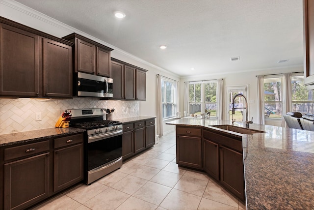 kitchen featuring sink, dark stone countertops, ornamental molding, appliances with stainless steel finishes, and decorative backsplash