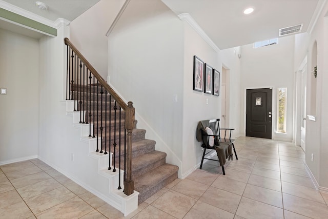 tiled entrance foyer featuring crown molding and a towering ceiling