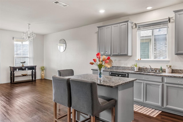 kitchen with sink, gray cabinetry, dark hardwood / wood-style floors, a kitchen breakfast bar, and a kitchen island