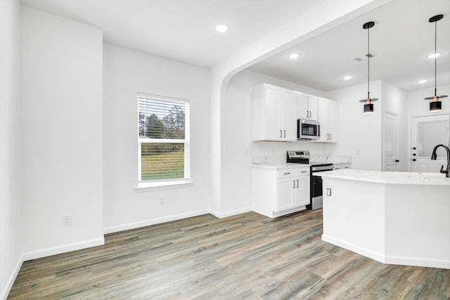 113 County Road 645, Kenefick, TX 77535 - kitchen with appliances with stainless steel finishes, pendant lighting, wood-type flooring, white cabinets, and light stone counters