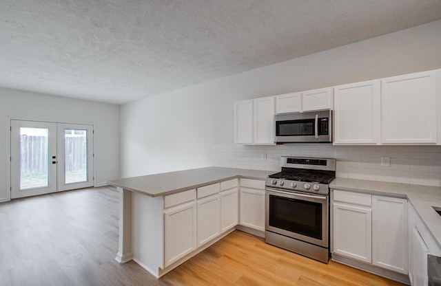 kitchen featuring white cabinetry, tasteful backsplash, kitchen peninsula, and appliances with stainless steel finishes