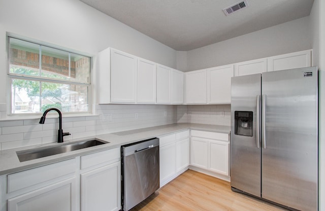 kitchen with stainless steel appliances, sink, white cabinets, and decorative backsplash