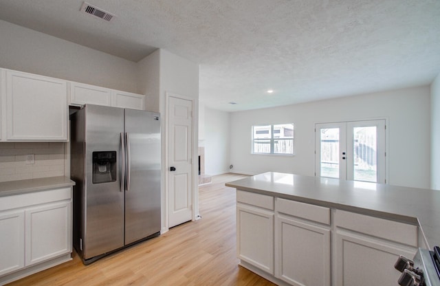 kitchen featuring light hardwood / wood-style flooring, backsplash, stainless steel refrigerator with ice dispenser, white cabinets, and french doors