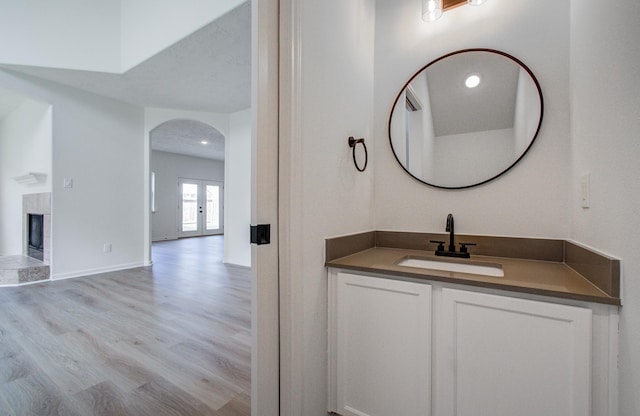 bathroom featuring vanity, a tiled fireplace, wood-type flooring, and french doors