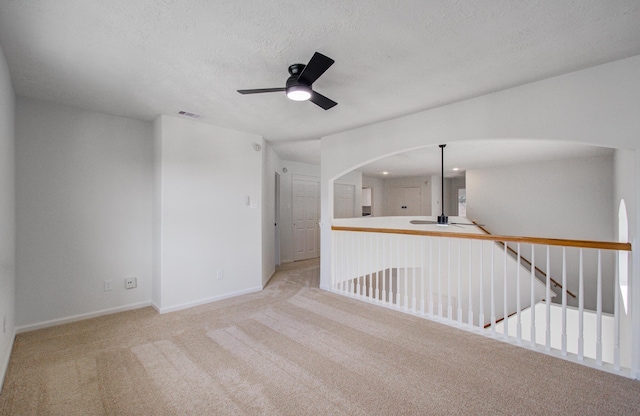 spare room featuring light carpet, a textured ceiling, and ceiling fan