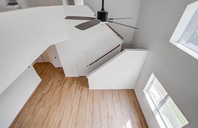 living room featuring ceiling fan, a high ceiling, and light wood-type flooring