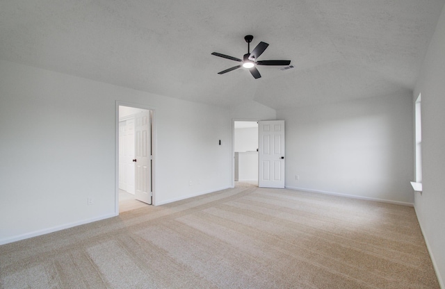 carpeted spare room with ceiling fan, vaulted ceiling, and a textured ceiling