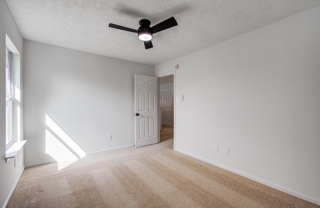 carpeted spare room featuring ceiling fan, a healthy amount of sunlight, and a textured ceiling