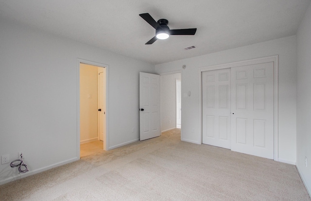 unfurnished bedroom featuring light carpet, a closet, and ceiling fan