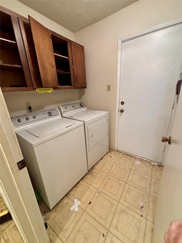 laundry room featuring cabinets, a textured ceiling, and washing machine and clothes dryer