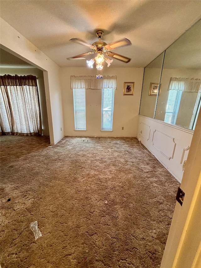 unfurnished room with ceiling fan, carpet flooring, and a textured ceiling