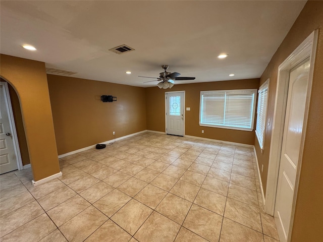 empty room with a healthy amount of sunlight, ceiling fan, and light tile patterned flooring