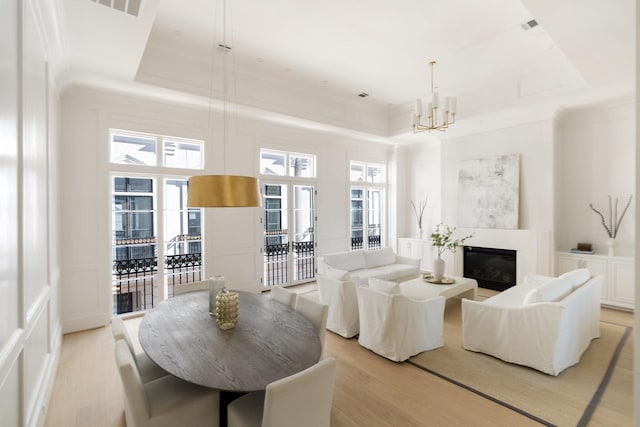 living room featuring a raised ceiling, a towering ceiling, a chandelier, and light wood-type flooring