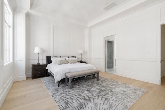 bedroom featuring ornamental molding, connected bathroom, and light wood-type flooring