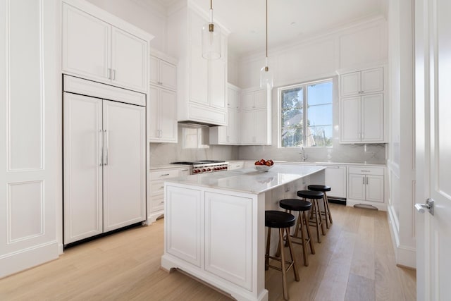 kitchen featuring hanging light fixtures, white cabinetry, a center island, and paneled refrigerator