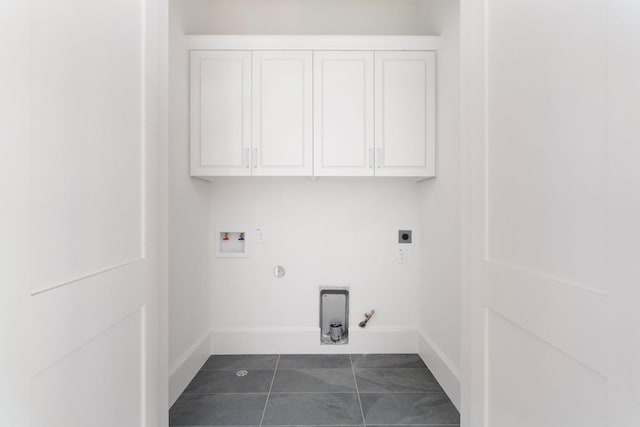 clothes washing area featuring gas dryer hookup, cabinets, dark tile patterned flooring, electric dryer hookup, and washer hookup