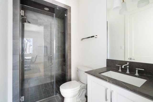 bathroom featuring vanity, a shower with shower door, and toilet