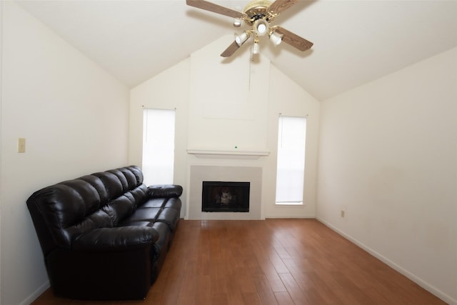 living area featuring baseboards, a large fireplace, lofted ceiling, and wood finished floors