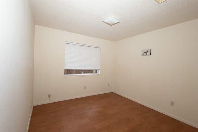 empty room with wood finished floors, baseboards, and a textured ceiling