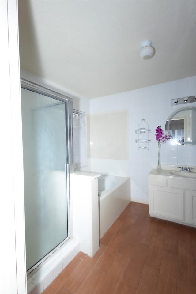 full bathroom with vanity, wood finished floors, a stall shower, tile walls, and a bath