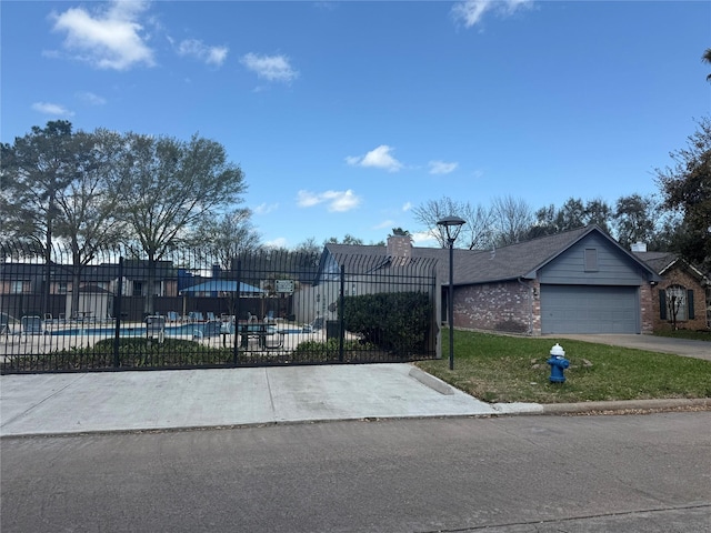 view of front of house featuring a front lawn, fence, concrete driveway, an attached garage, and brick siding