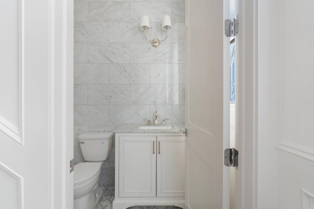 bathroom featuring vanity, toilet, and tile walls