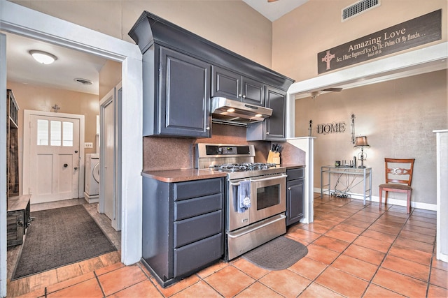 kitchen featuring light tile patterned flooring, stainless steel range with gas stovetop, washer / clothes dryer, and decorative backsplash