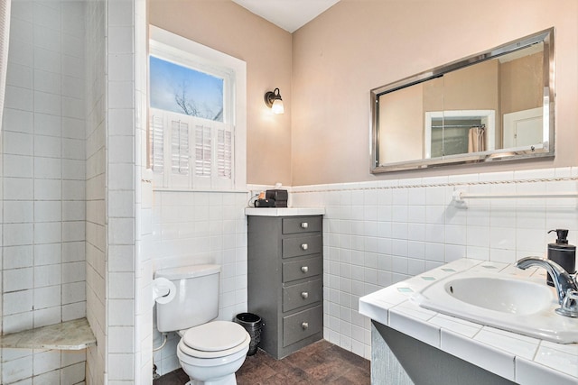 bathroom with vanity, tile walls, and toilet