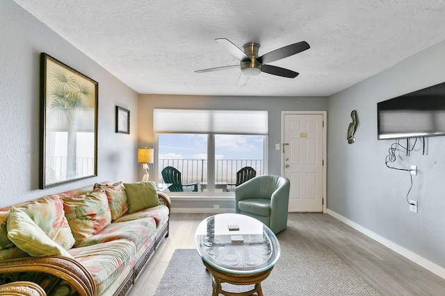 living room featuring a textured ceiling, ceiling fan, and light hardwood / wood-style flooring