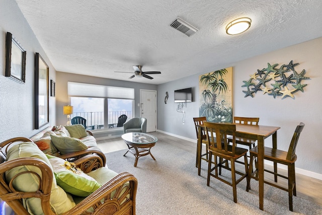 living room with a textured ceiling, wood-type flooring, and ceiling fan