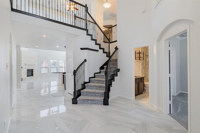 stairway with a towering ceiling and a large fireplace