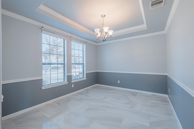 empty room with a raised ceiling, ornamental molding, and a notable chandelier