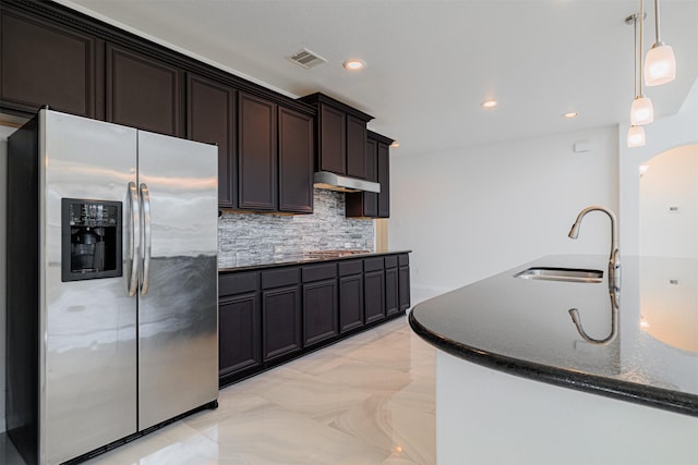 kitchen with dark brown cabinetry, sink, pendant lighting, stainless steel appliances, and backsplash