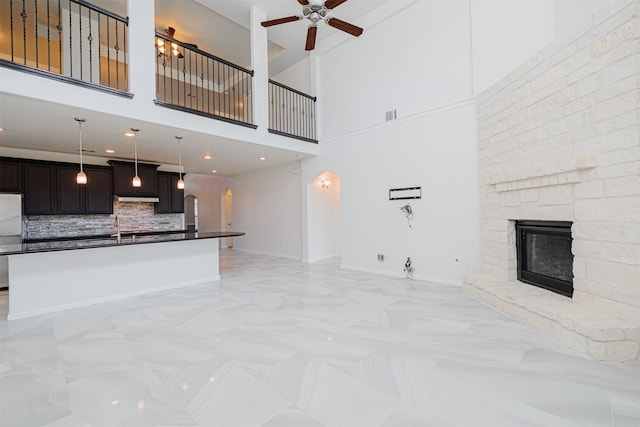 unfurnished living room featuring a stone fireplace and ceiling fan