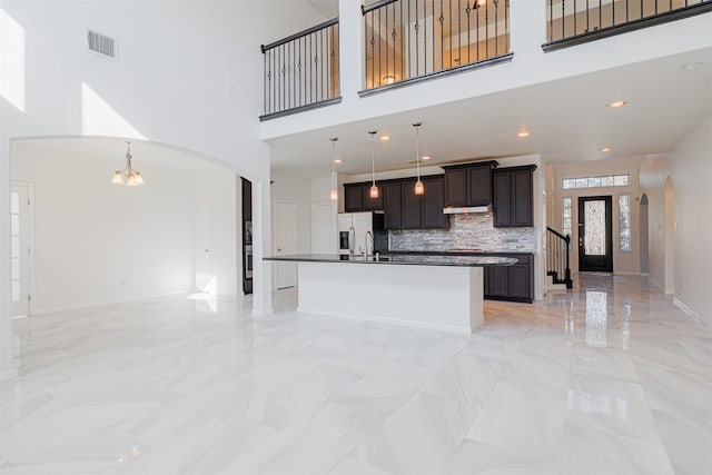 kitchen featuring decorative light fixtures, sink, a kitchen island with sink, stainless steel fridge with ice dispenser, and an inviting chandelier