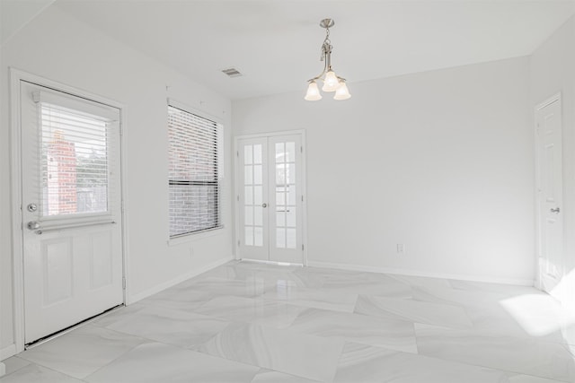 unfurnished room with a notable chandelier and french doors