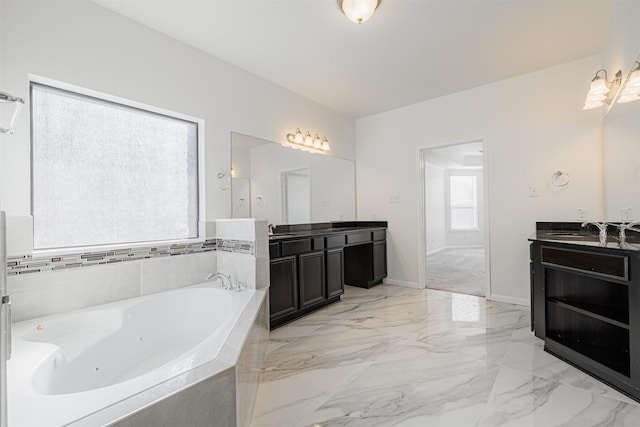 bathroom featuring a relaxing tiled tub and vanity