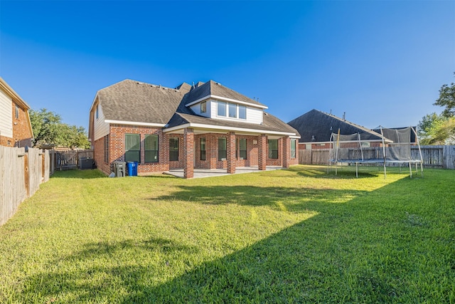 back of house featuring a patio, a yard, a trampoline, and central air condition unit