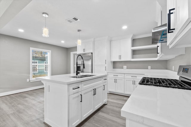 kitchen with light hardwood / wood-style flooring, a kitchen island with sink, hanging light fixtures, white cabinetry, and stainless steel appliances