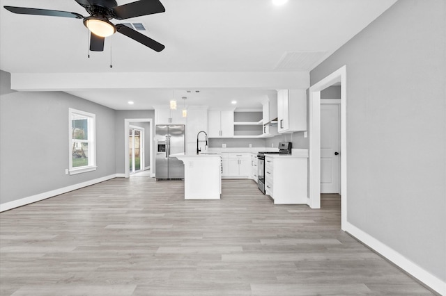 kitchen featuring appliances with stainless steel finishes, white cabinetry, sink, hanging light fixtures, and a kitchen island with sink