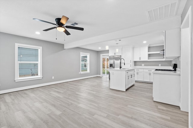 kitchen with stainless steel refrigerator with ice dispenser, light hardwood / wood-style flooring, a center island with sink, and white cabinets